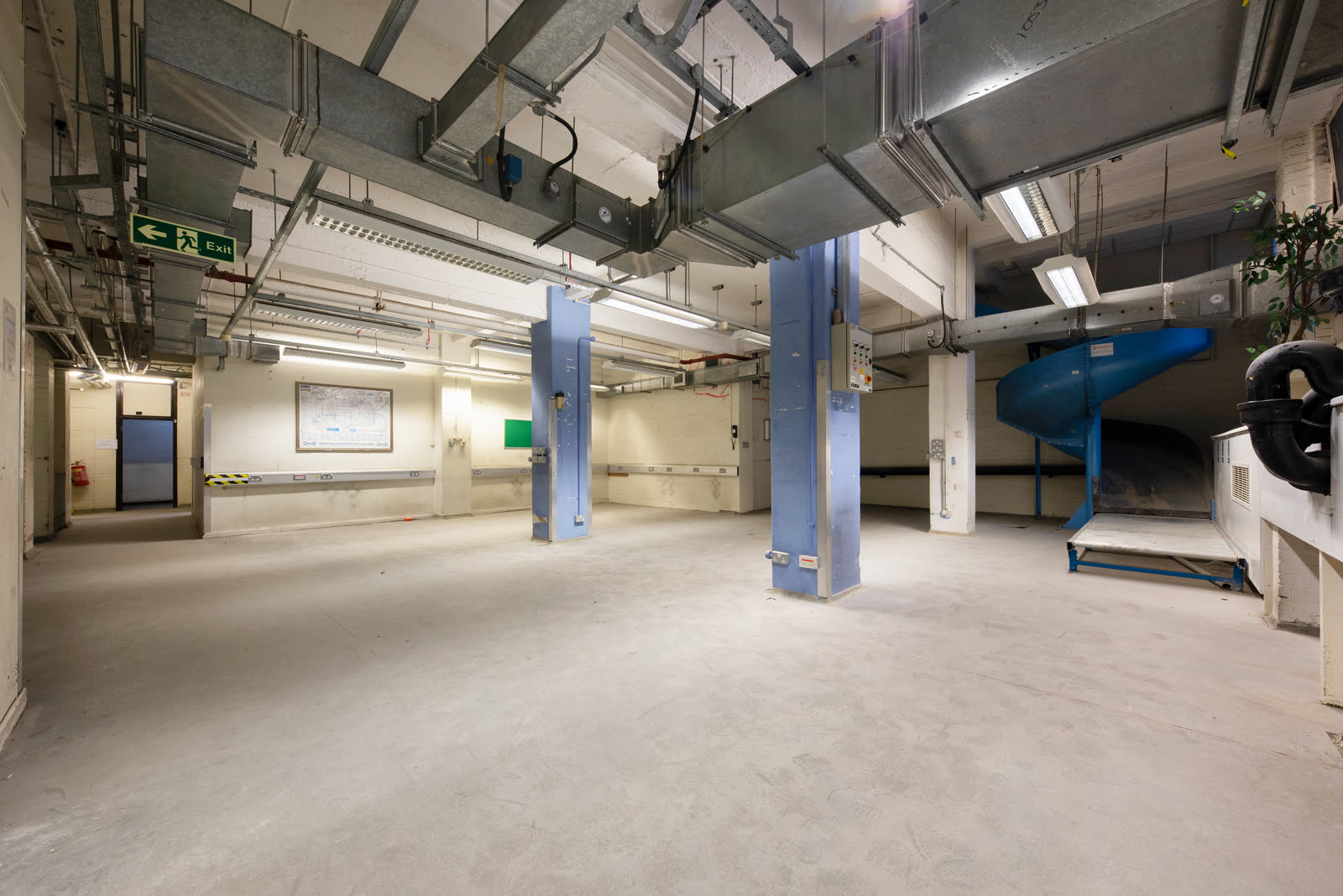 200 Baker Street basement, empty industrial space with blue painted columns and exposed services