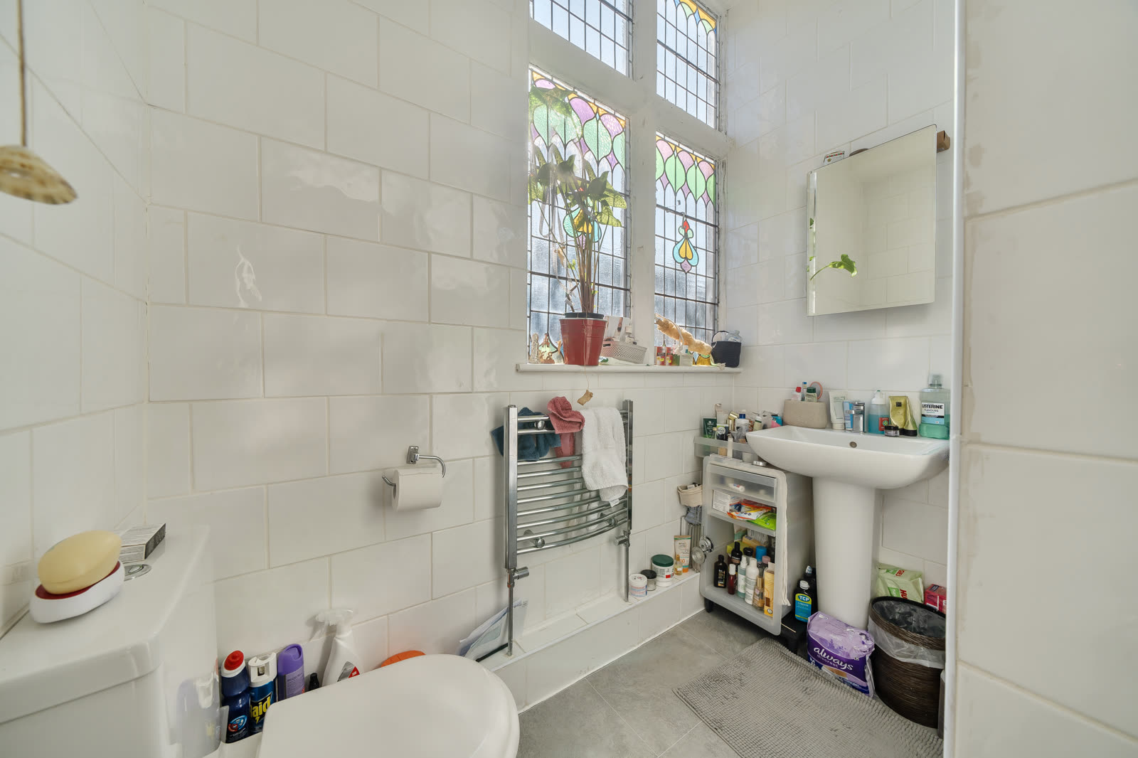 Bathroom as photographed, lived-in clutter on the sink and radiator, occupied