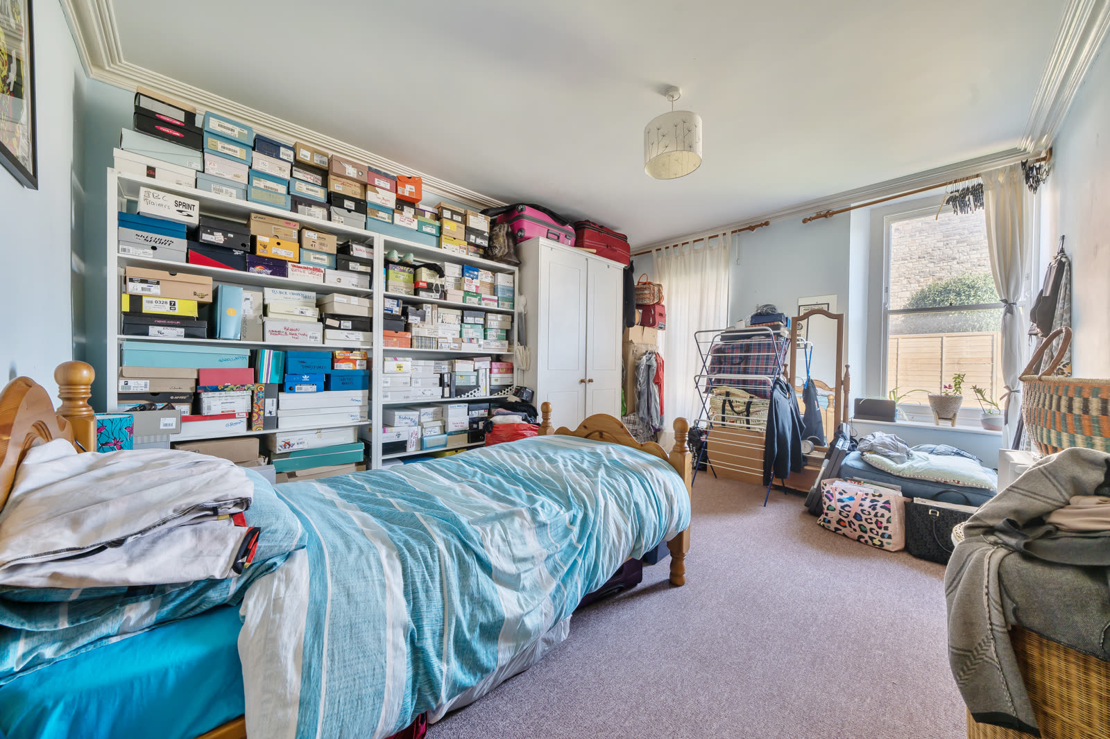 Bedroom as photographed, with floor-to-ceiling shoe-box shelving, clutter, single bed