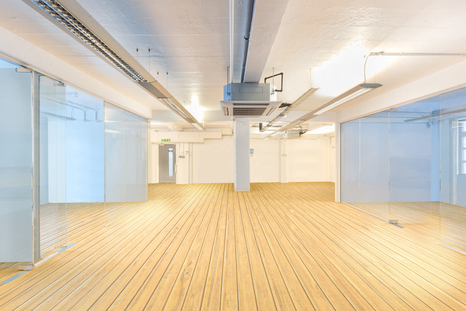 Same office digitally cleared. Monitors, desks and clutter removed, glass partitions and bare floor revealed for prospective tenants
